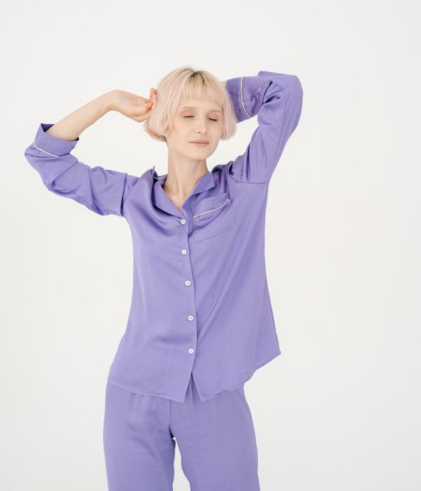 Woman in a calm, flowing pose with soft purple light.
